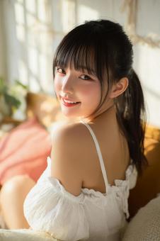 窓辺で微笑む清楚な若者女性の写真