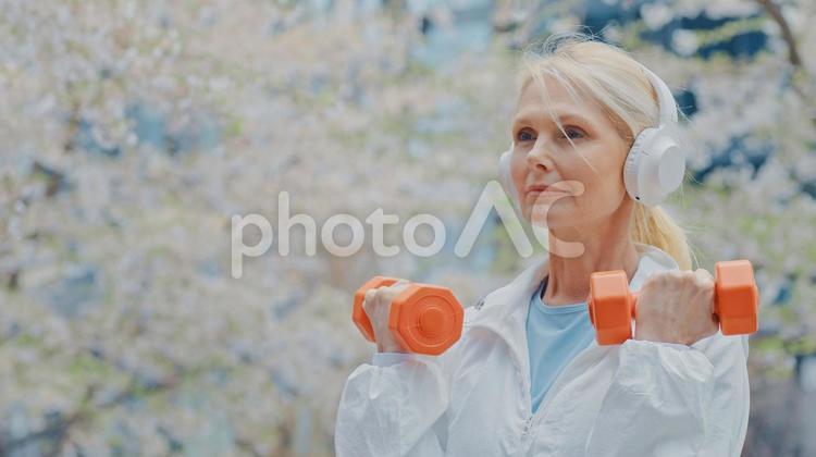 ダンベルを桜のそばでするシニア女性 女性,人物,元気の写真素材