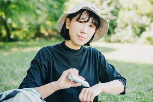 外で紫外線予防で日焼け止めを塗る女性 外で紫外線予防で日焼け止めを塗る女性 日焼け止め,日焼け止めクリーム,uvの写真素材