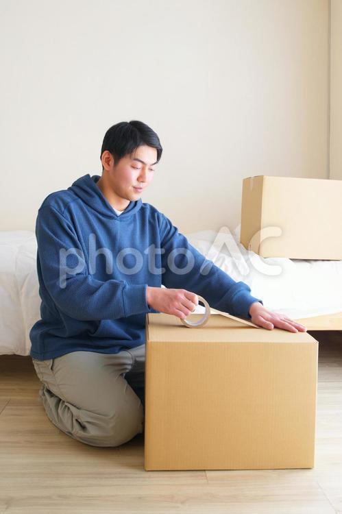 段ボール箱をテープで閉じる男性 引っ越し,一人暮らし,男性の写真素材