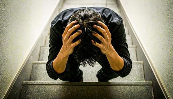 頭を抱えて落ち込む日本人男性 頭を抱えて落ち込む日本人男性の写真