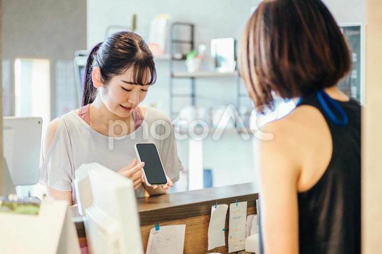 受付でスマホを出す女性 スマホ,受付,ポイントの写真素材