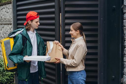 フードデリバリーの男性から料理を受け取る女性 配達,フードデリバリー,デリバリーの写真素材