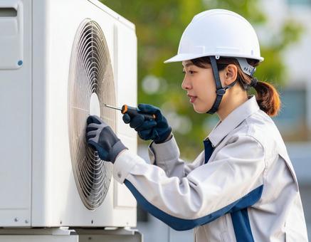 エアコン室外機を修理する女性技術者 エアコン室外機を修理する女性技術者の写真