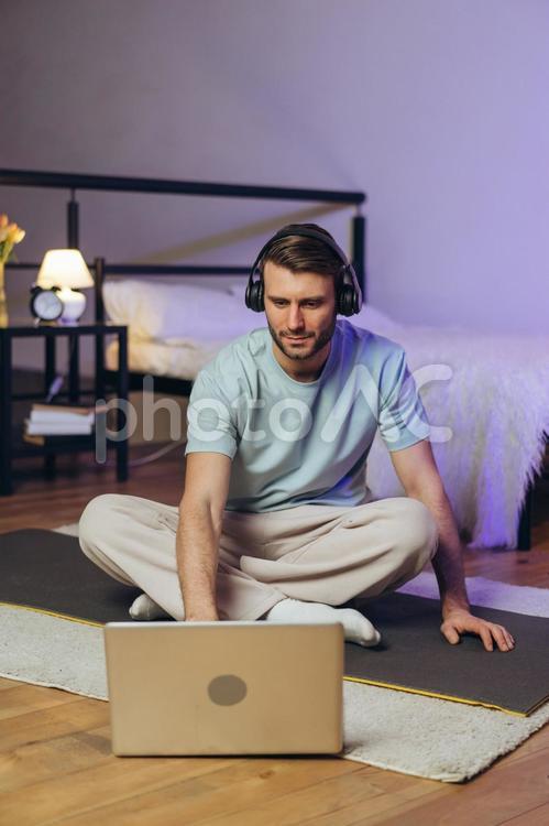 ヘッドフォンをしてパソコンを真剣に見る男性 男性,ヒゲ,ヨガの写真素材
