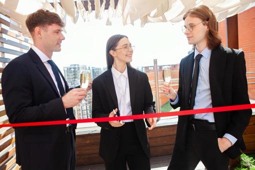 シャンパンを持つ男性とハサミを持ち笑う女性 男女,テープカット,赤の写真素材