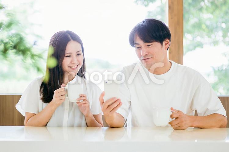 ダイニングでスマホを使う男女 スマホ,夫婦,スマートフォンの写真素材