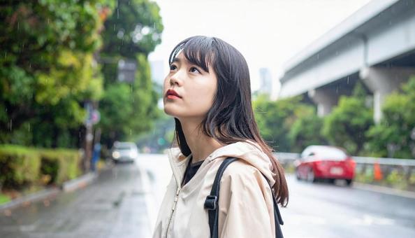 雨の中バス停でバスを待つ日本人女性 雨の中バス停でバスを待つ日本人女性の写真