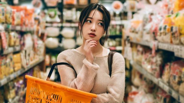スーパーで買い物に悩む女性の日常シーン スーパーで買い物に悩む女性の日常シーンの写真