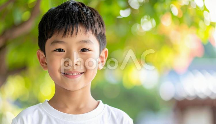 少年のポートレート　緑の背景　木漏れ日 少年,夏,ポートレートの写真素材