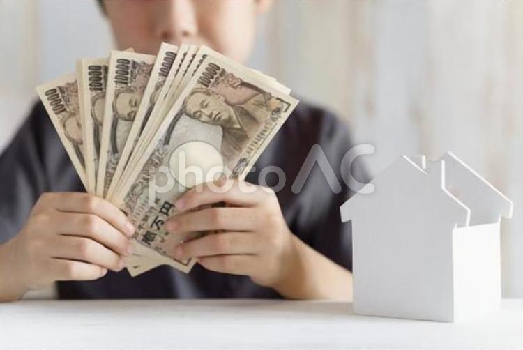 1万円札を持つ小学生の男の子と家の小物 子供,マイホーム,将来設計の写真素材