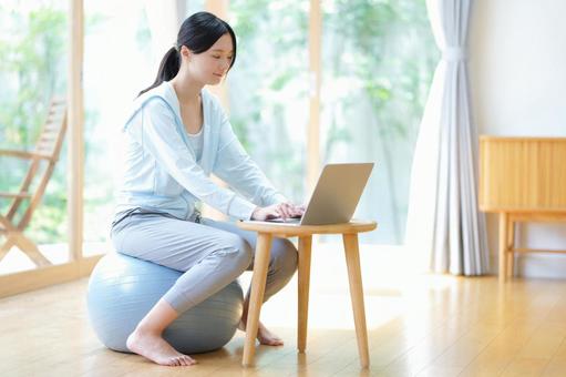 リビングでボールに座りパソコン作業中の女性 女性,バランスボール,微笑むの写真素材