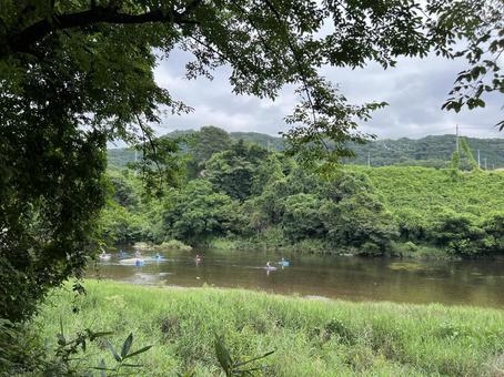 川でカヌーを楽しむ人々と緑豊かな風景 川でカヌーを楽しむ人々と緑豊かな風景の写真