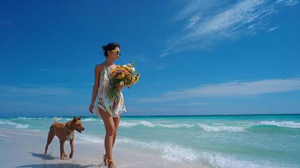 花束を抱え、ビーチで海を眺める美しい女性の写真