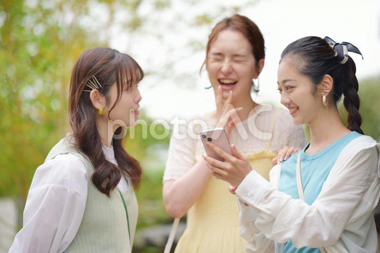 公園でスマートフォンを見ている3人の女性 女子旅,女性,日本人の写真素材