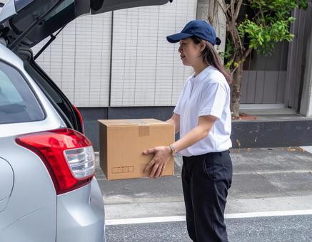 荷物を下ろす配達員 荷物を下ろす配達員の写真