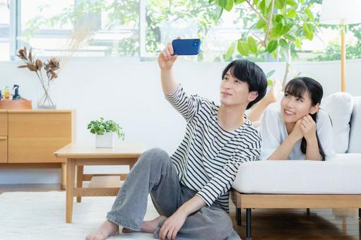 リビングでスマホを見る若いカップル リビングでスマホを見る若いカップル 夫婦,カップル,リビングの写真素材
