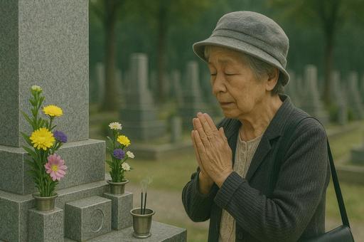 墓前で手を合わせる高齢の女性の写真