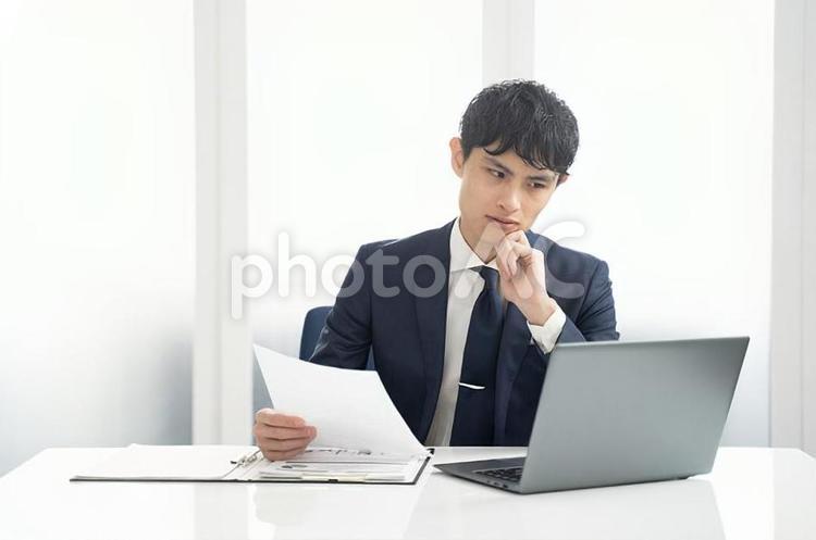 パソコンと書類チェックするビジネス男性 ビジネス,オフィス,デスクワークの写真素材