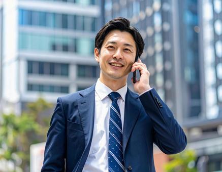 街中で電話をかけるビジネスマンの写真