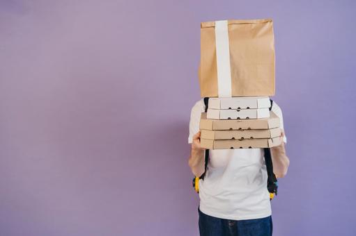 ピザの箱と紙袋を重ねて持つ男性（紫背景） 配達,デリバリー,配送の写真素材