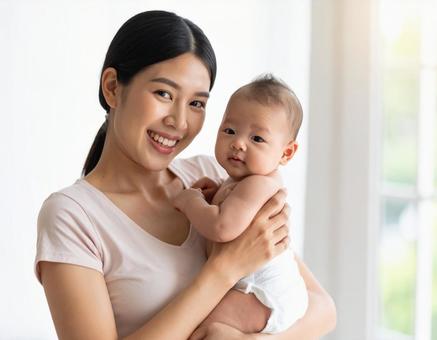 笑顔で赤ちゃんを抱く若い母親 笑顔で赤ちゃんを抱く若い母親の写真