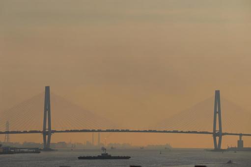 吊り橋と工場地帯と大型船舶と海の夕空 吊り橋と工場地帯と大型船舶と海の夕空の写真