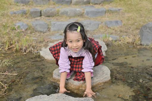 小川の水に手を浸す笑顔の女の子　春秋１ 川,水,水遊びの写真素材