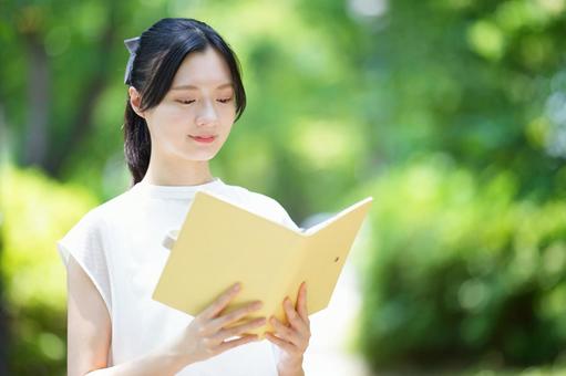 白いノースリーブワンピースの女性が笑顔で本を広げる 女性,本,持つの写真素材