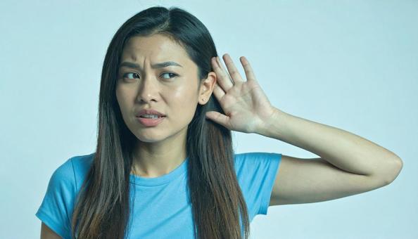 音をよく聞こうと耳をそばだてる女性 音をよく聞こうと耳をそばだてる女性の写真