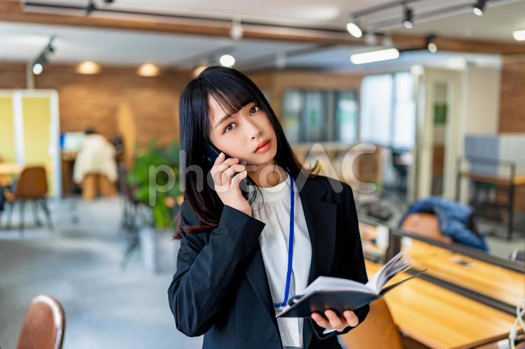 電話しながら見つめてくるビジネスウーマン 女性,ビジネス,ビジネスウーマンの写真素材