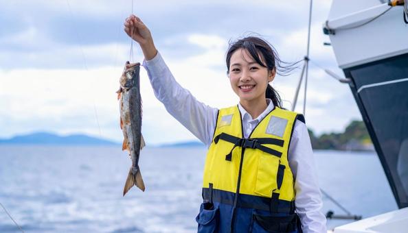 釣りを楽しむライフジャケットを着た女性 釣りを楽しむライフジャケットを着た女性の写真