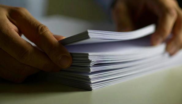 重なった白いコピー用紙をめくる手 重なった白いコピー用紙をめくる手の写真