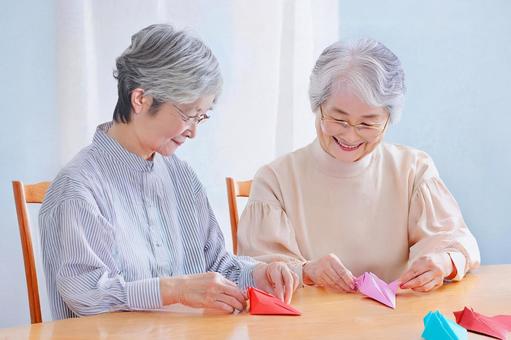 折り紙を折る高齢女性の写真