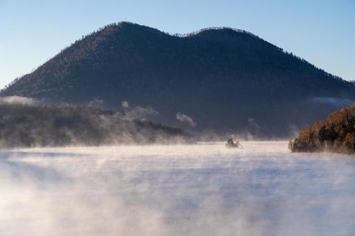 早朝の静寂に包まれた湖面を流れる霧 然別湖,神秘的,水蒸気の写真素材