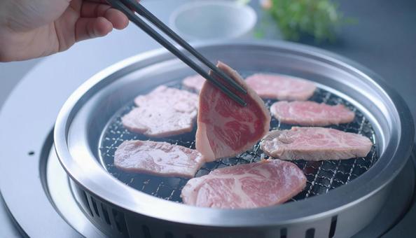 焼肉を鉄板で焼いて鉄箸ですくう 焼肉を鉄板で焼いて鉄箸ですくうの写真