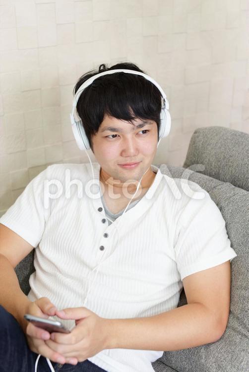くつろぐ男性 スマホ,スマートフォン,ヘッドフォンの写真素材