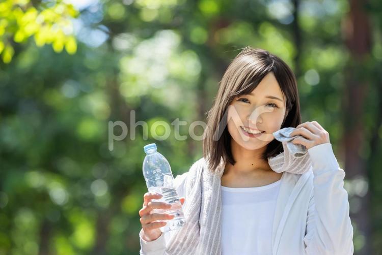 タオルで汗を拭って水分補給する女性 水分補給,有酸素運動,ペットボトルの写真素材