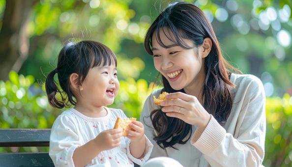 公園でおやつを食べる親子 公園でおやつを食べる親子の写真