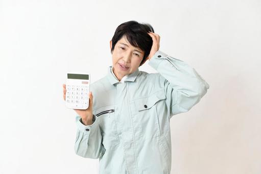 電卓を持ちながら困る作業服姿の中高年女性 作業員,女性,ミドル女性の写真素材