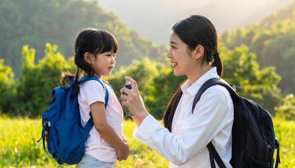 子供に虫除けスプレーをつけるお母さん 子供に虫除けスプレーをつけるお母さんの写真