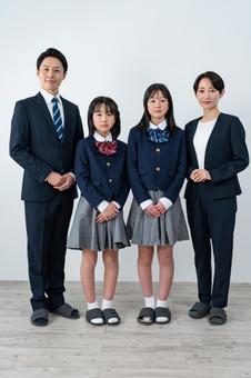 スーツを着た男女と制服を着た女の子二人 スーツを着た男女と制服を着た女の子二人 入学式,父母,母親の写真素材