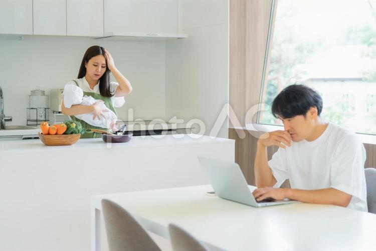 テレワークする男性と赤ちゃんと抱く女性 ストレス,夫婦喧嘩,育児の写真素材