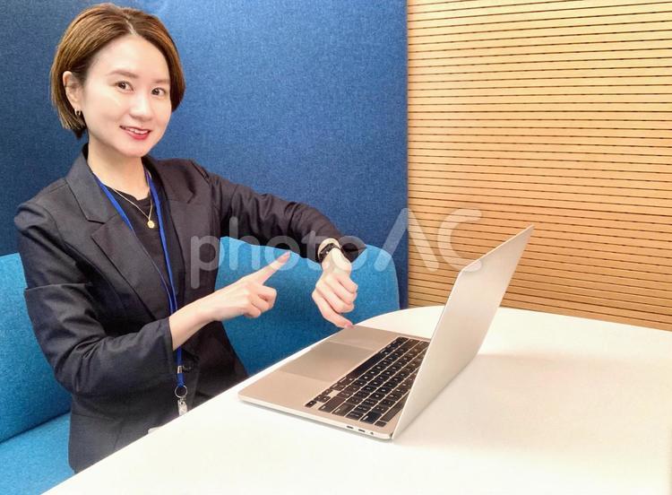 会議室で仕事をしながら時計を指差す女性 女性,笑顔,パソコンの写真素材