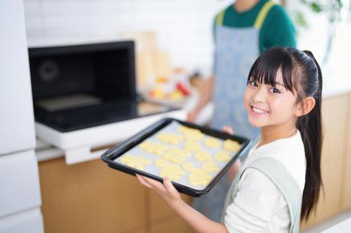 焼き菓子をオーブンで焼く親子の手元 女の子,日本人,クッキーの写真素材