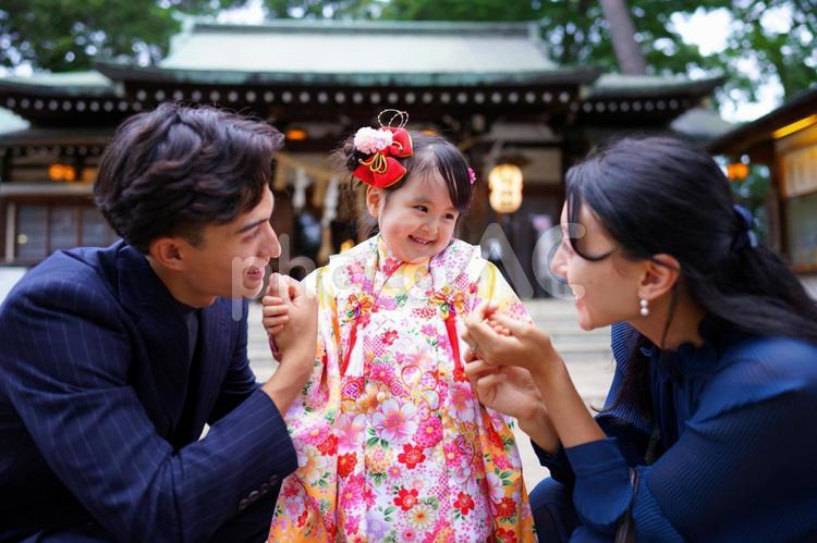 神社の前で笑顔をはじけさせる着物姿の女の子 七五三,お参り,七五三参りの写真素材