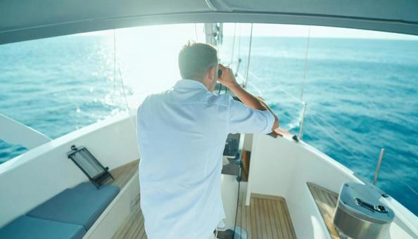双眼鏡で海の先を見ている男性 双眼鏡で海の先を見ている男性の写真
