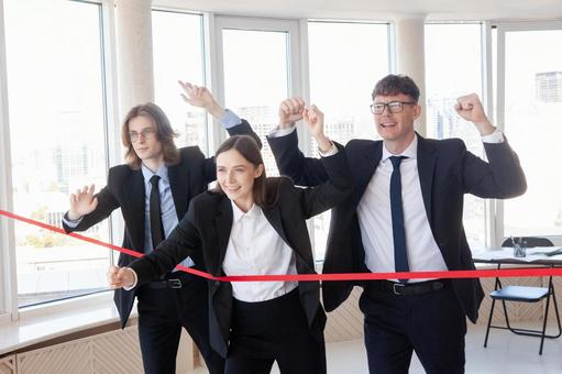 赤いテープの前で喜ぶスーツの男女 男女,外国人,ビジネスの写真素材