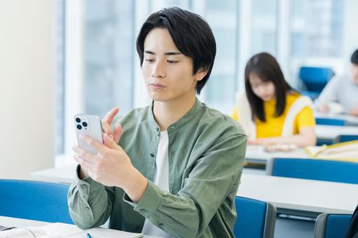 教室でスマホを見る大学生 スマホ,笑顔,大学生の写真素材