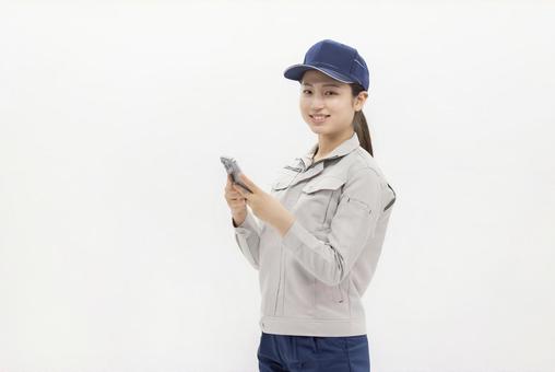 スマートフォンを使う作業服の女性 スマートフォンを使う作業服の女性 女性,ビジネスウーマン,スマートフォンの写真素材